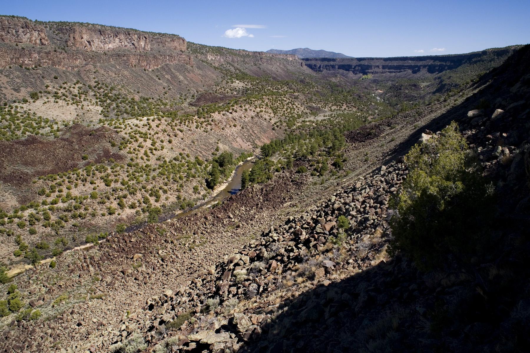 Wide view of a deep, rocky canyon with a river below.