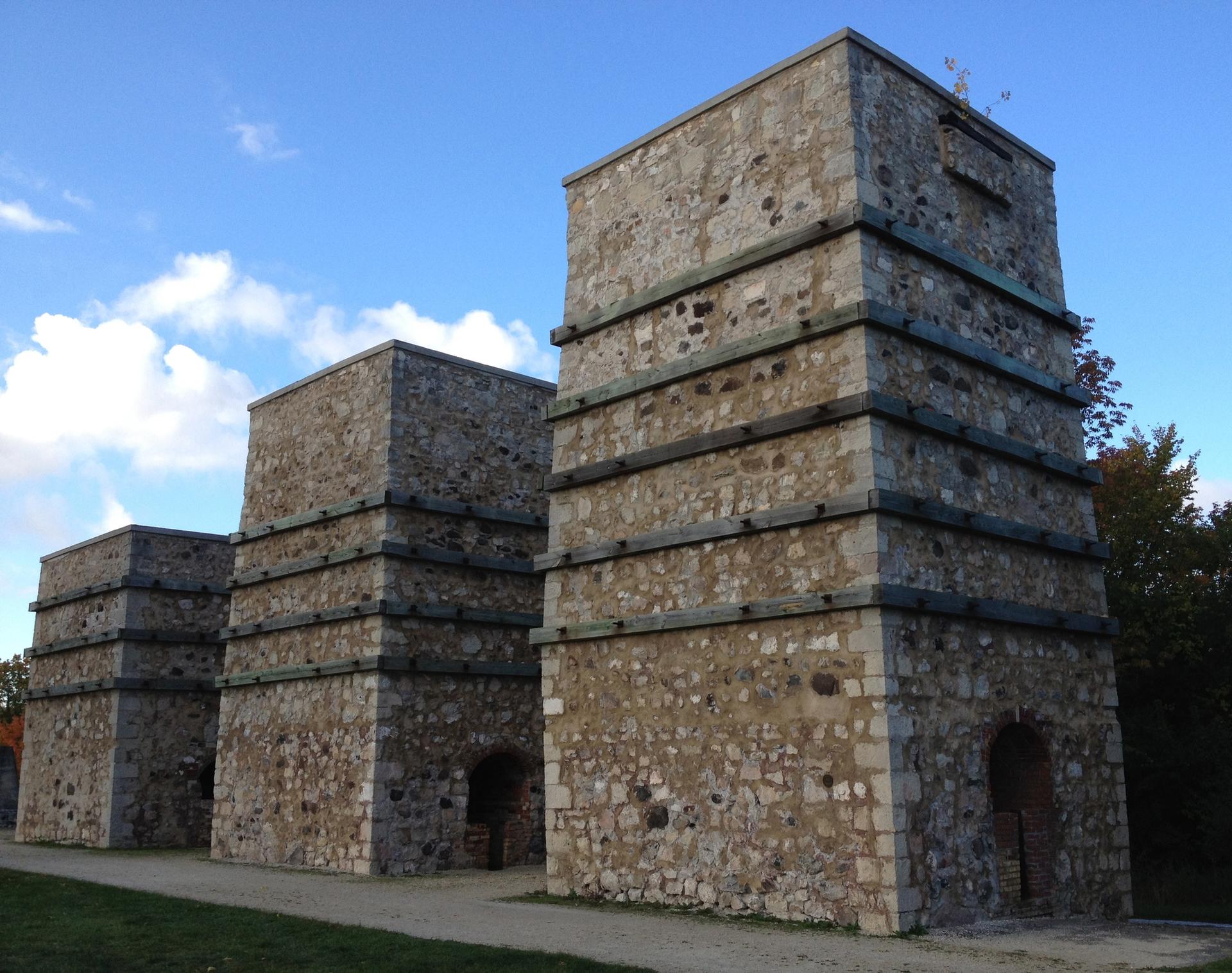 Three large, old stone structures stand under a blue sky.