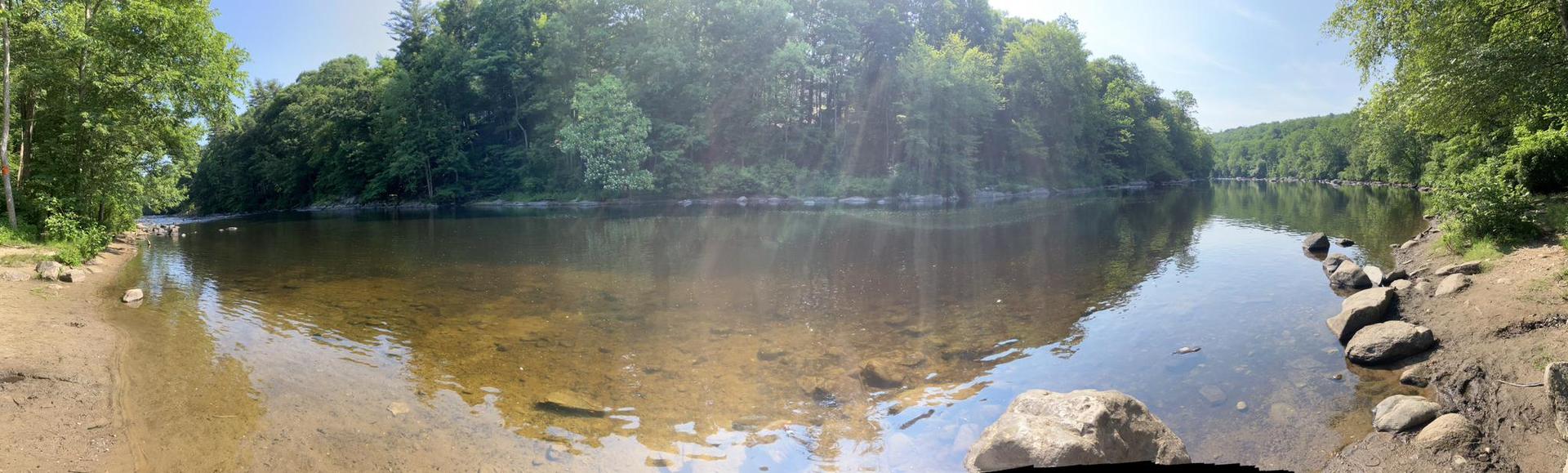 Panoramic view of a shallow river with trees reflecting on the water.