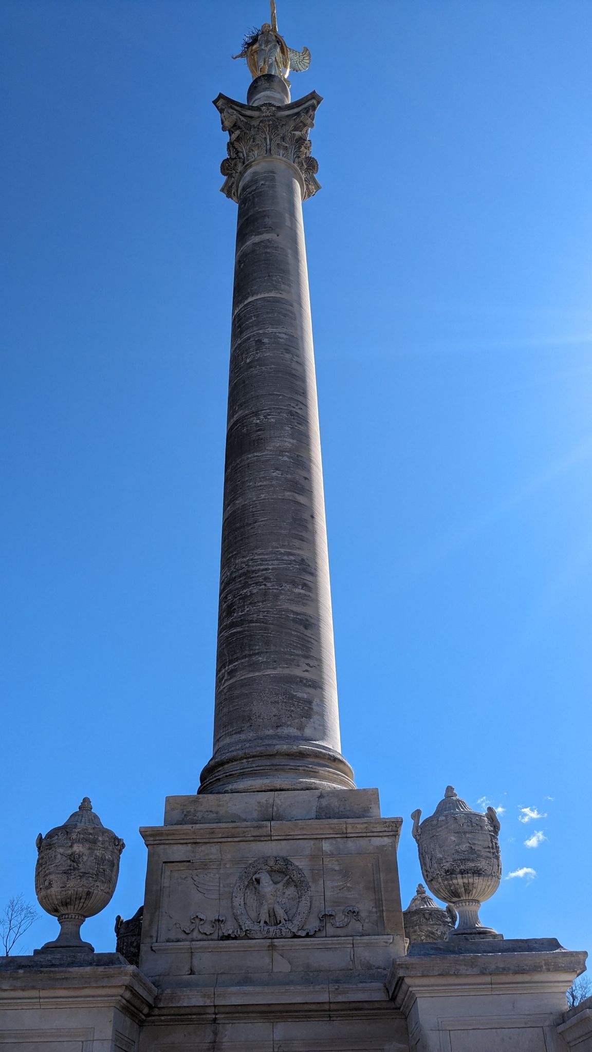 Tall stone column with a statue on top, against a bright blue sky. - Mosholu-Pelham Greenway and Pelham Bay Park Loop