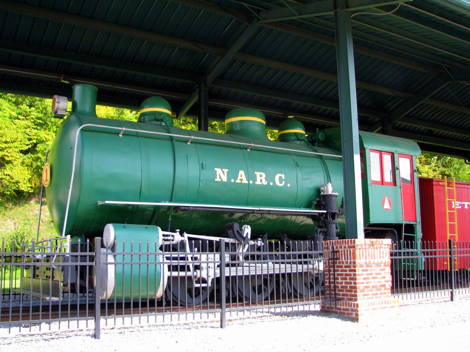 Brightly lit green train engine, N.A.R.C., under a shelter.
