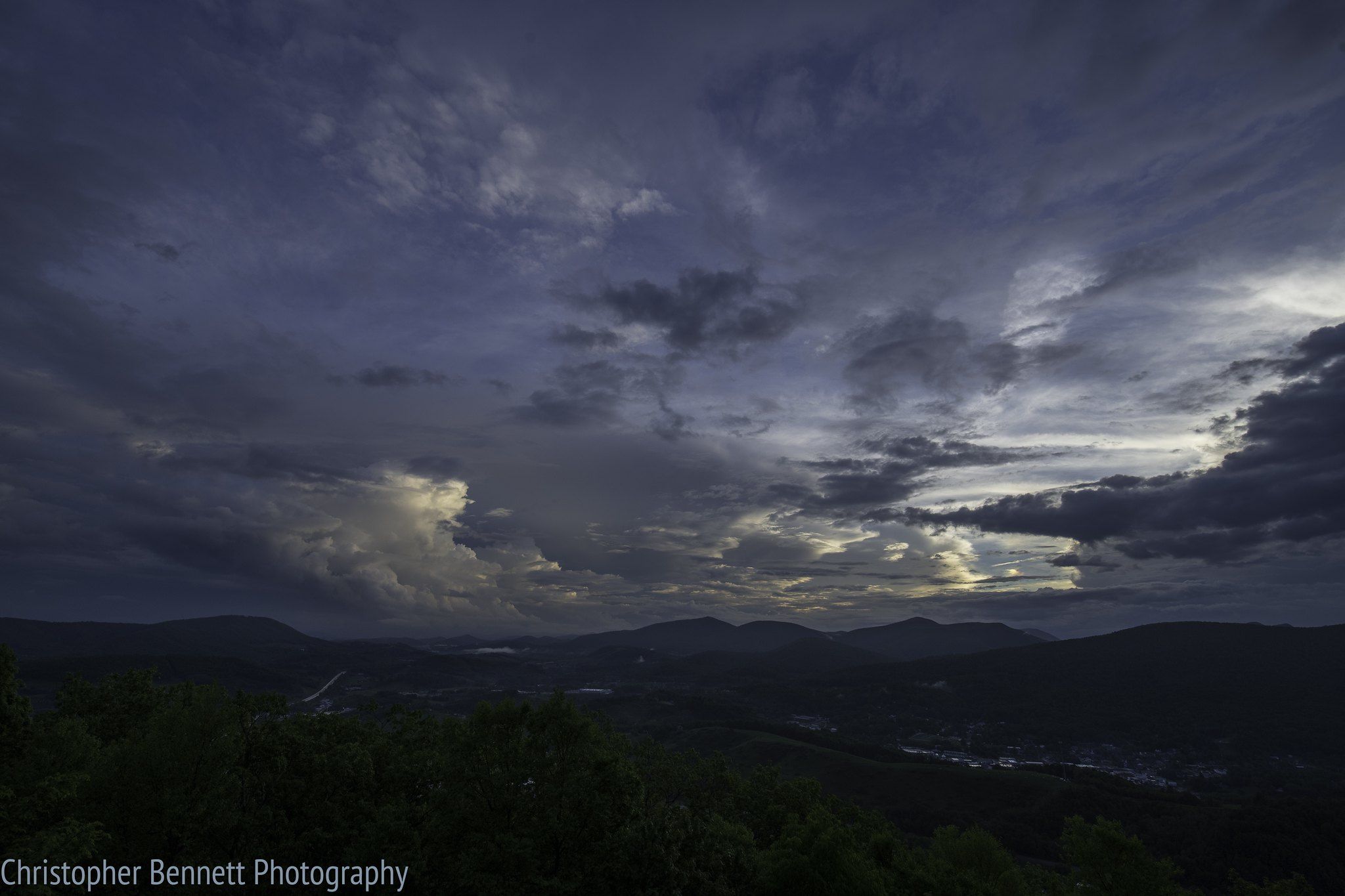 Dramatic dark clouds over a mountain landscape with distant valley lights at dusk. - Summit Trail and Luther Rock via Mountain Ridge Trail