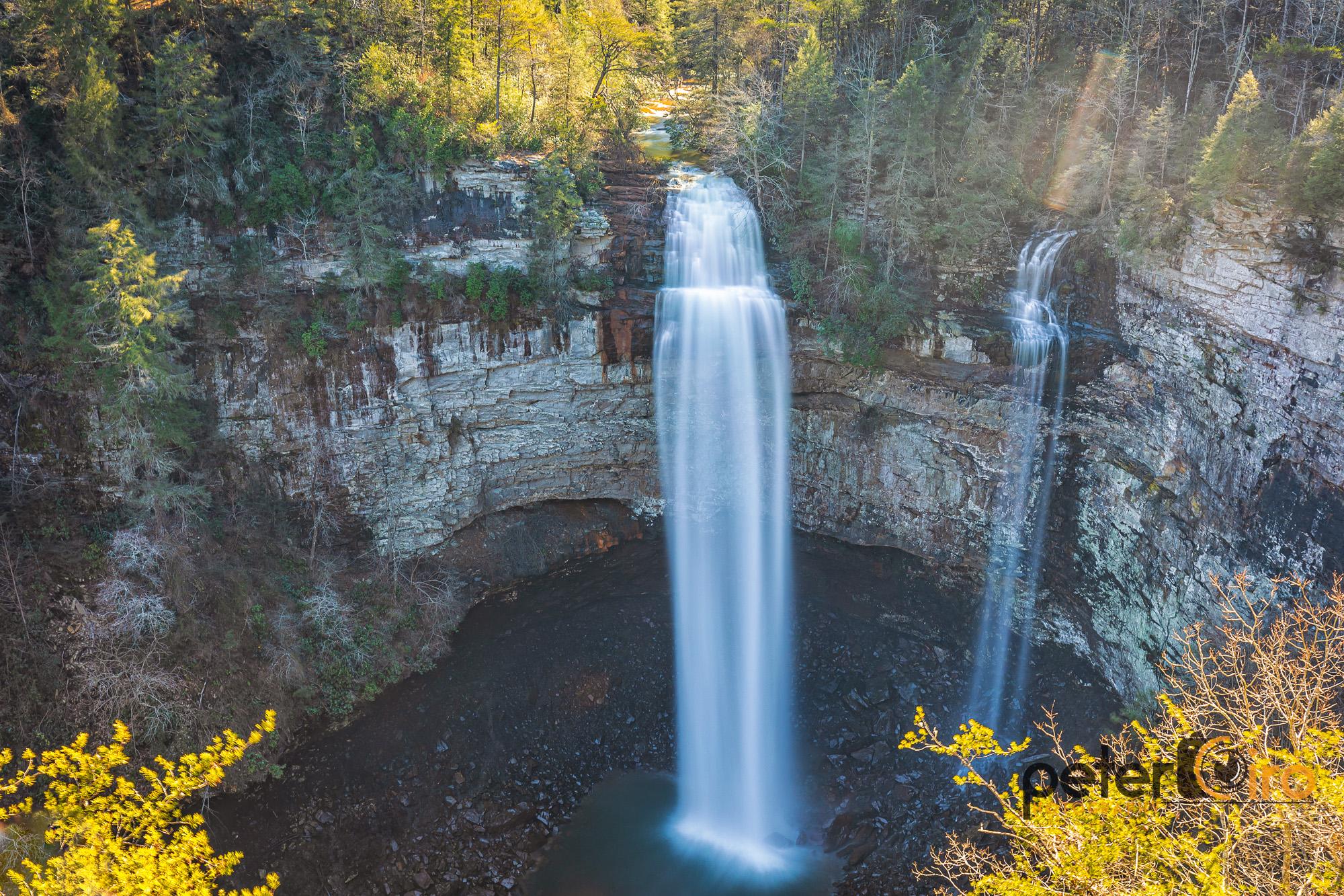 Majestic waterfall plunges from a rocky cliff into a dark pool.