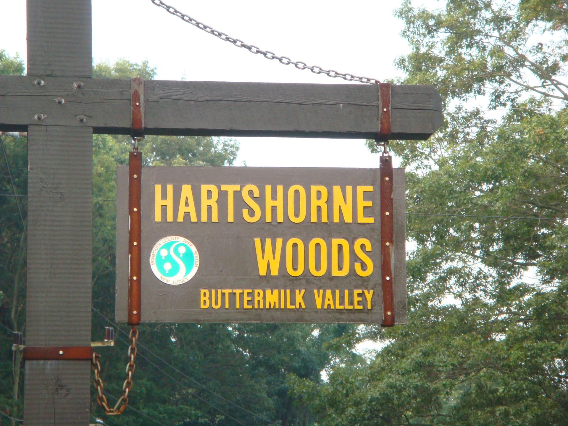 A brown wooden sign with yellow text hangs from a wooden post.