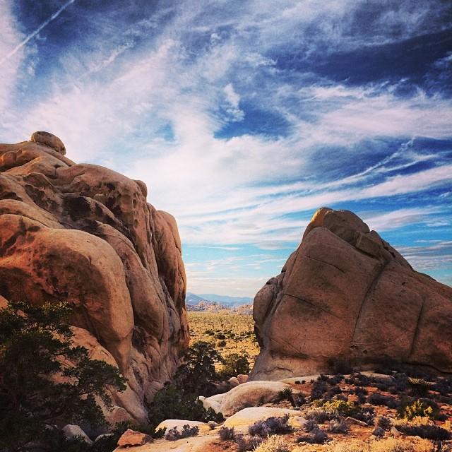 Dramatic desert rock formations under a vibrant, cloudy sky.