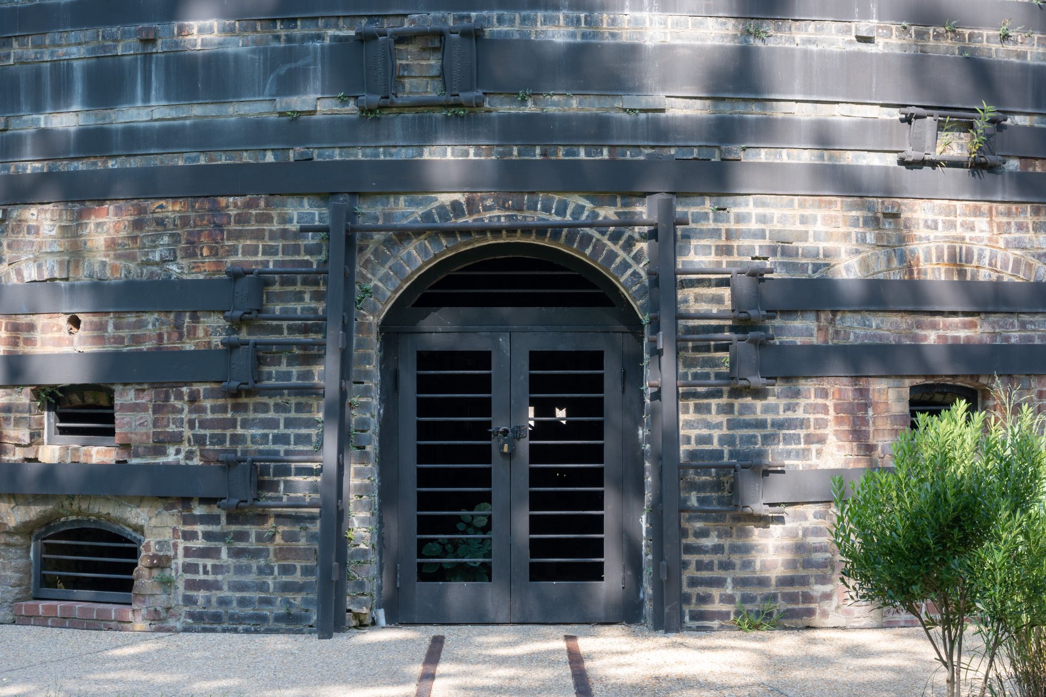 Arched metal doors on an old brick building with horizontal metal bands. - Occoquan River views loop from Occoquan