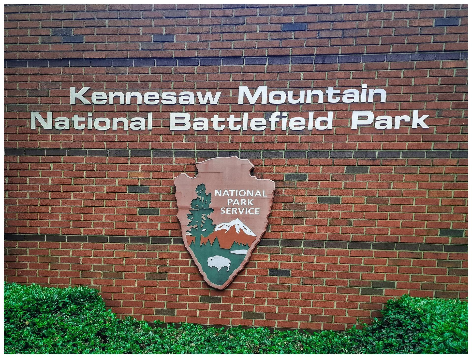 Brick wall with a park sign and a National Park Service emblem.