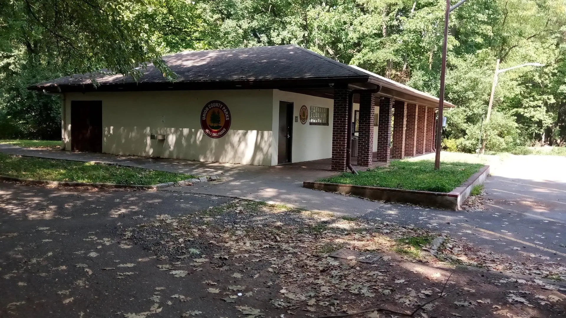 A single-story building with a dark roof, surrounded by trees and pavement.