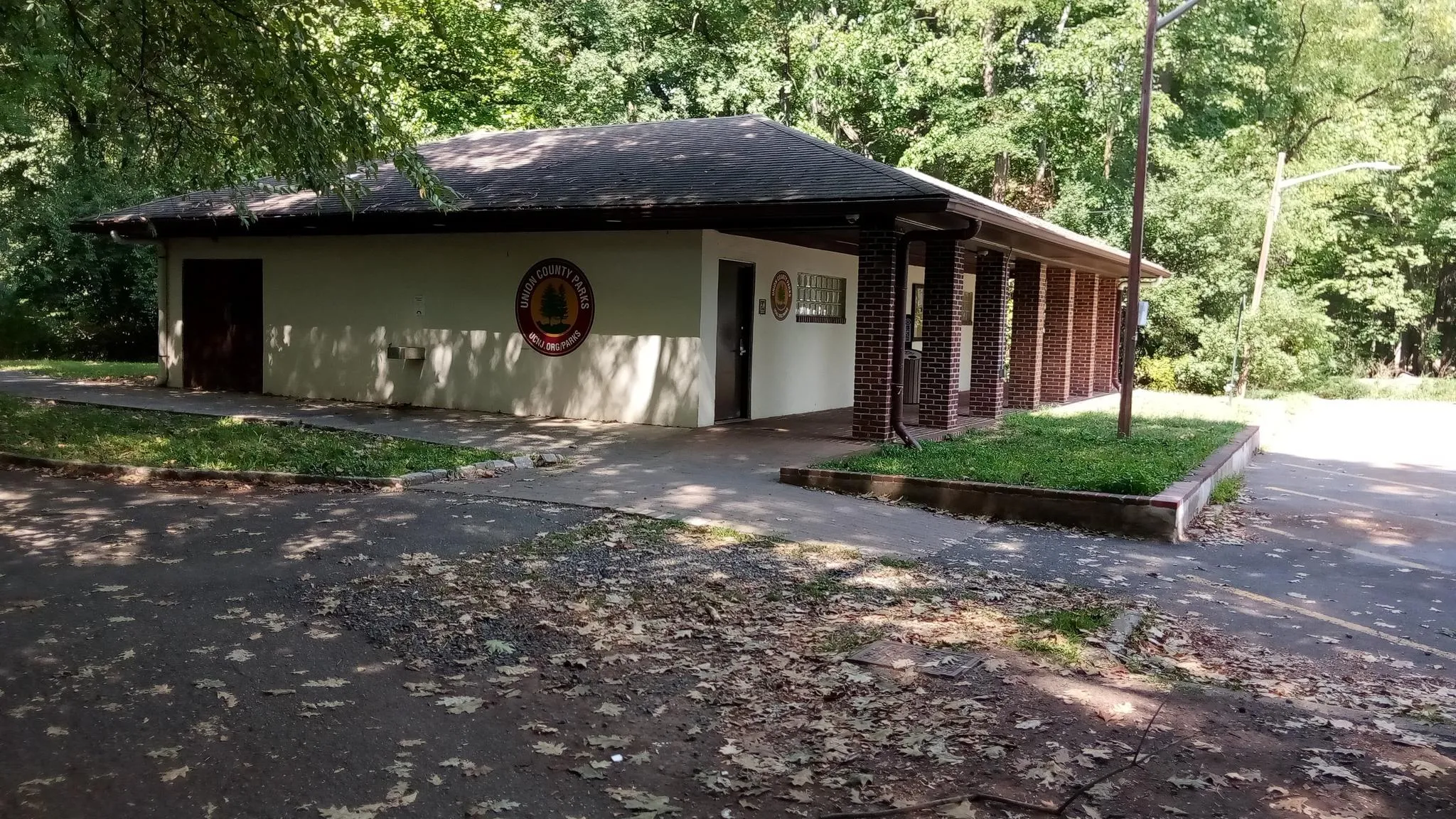 A single-story building with a dark roof, surrounded by trees and pavement. - Nomahegan Park & Lower Echo Lake — Union County