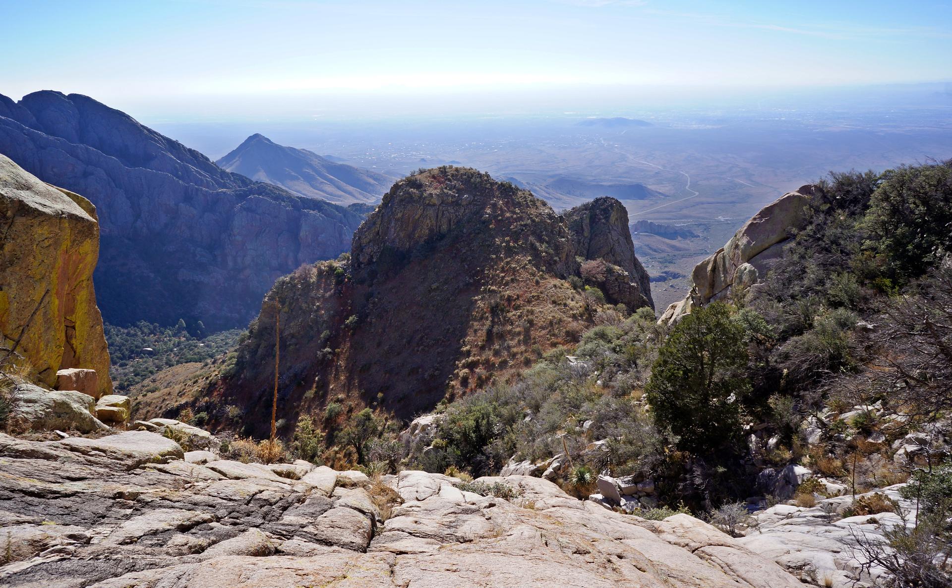 Expansive mountain panorama from a rocky viewpoint, with valleys and distant peaks.