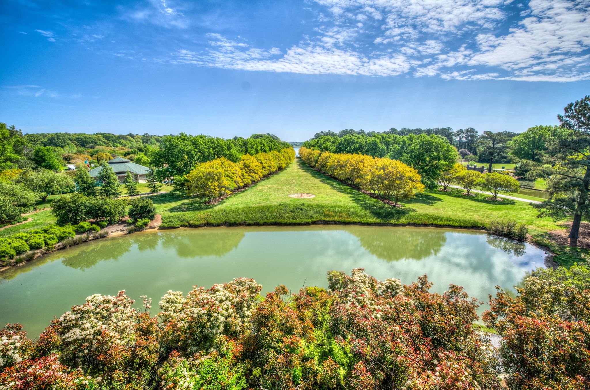 Bright sunny day over a manicured garden with a reflective pond and trees. - Ocean View and East Beach loop