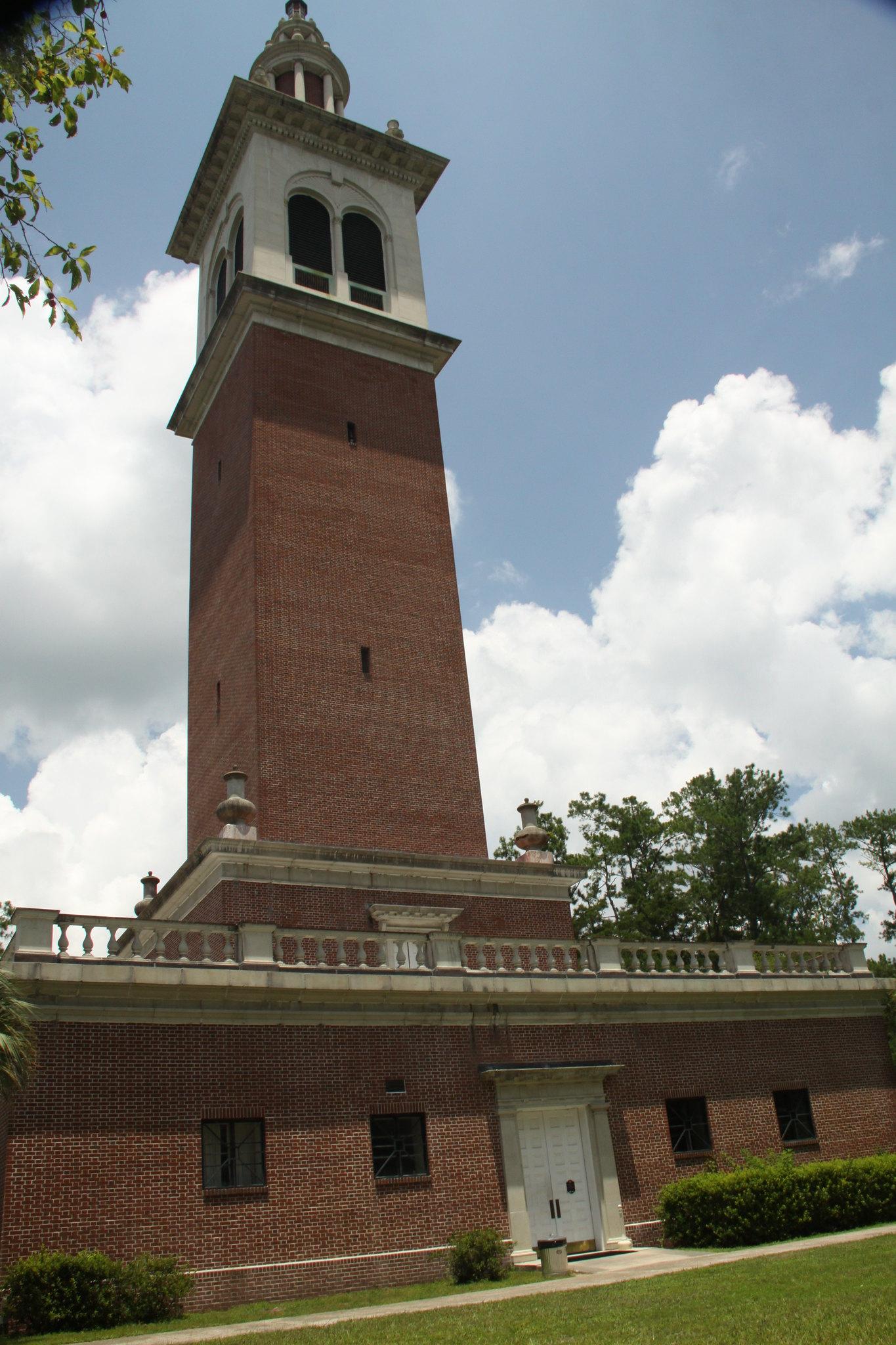 A tall brick tower with a white top against a cloudy blue sky.