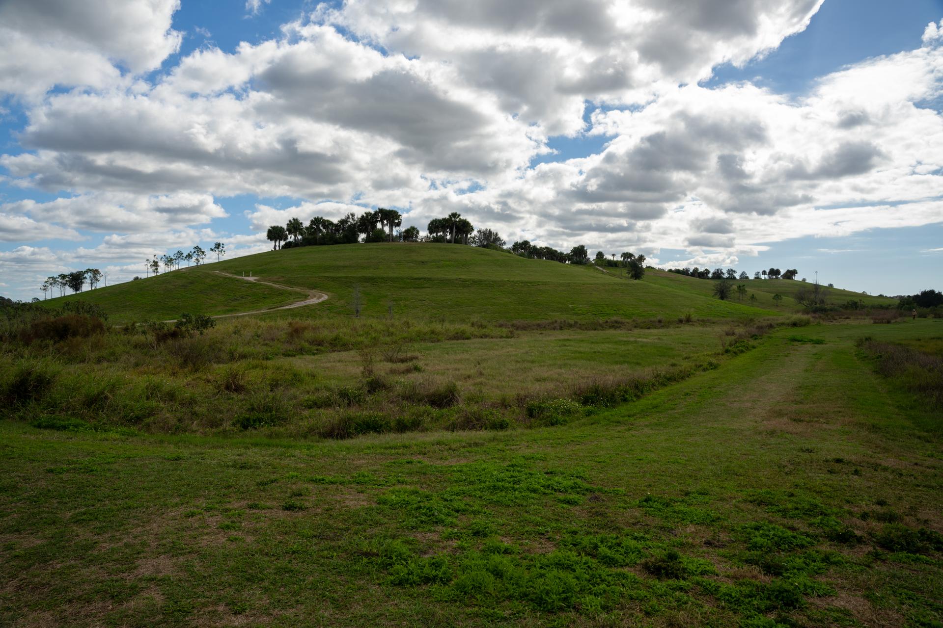 Wide view of rolling green hills under a partly cloudy sky.