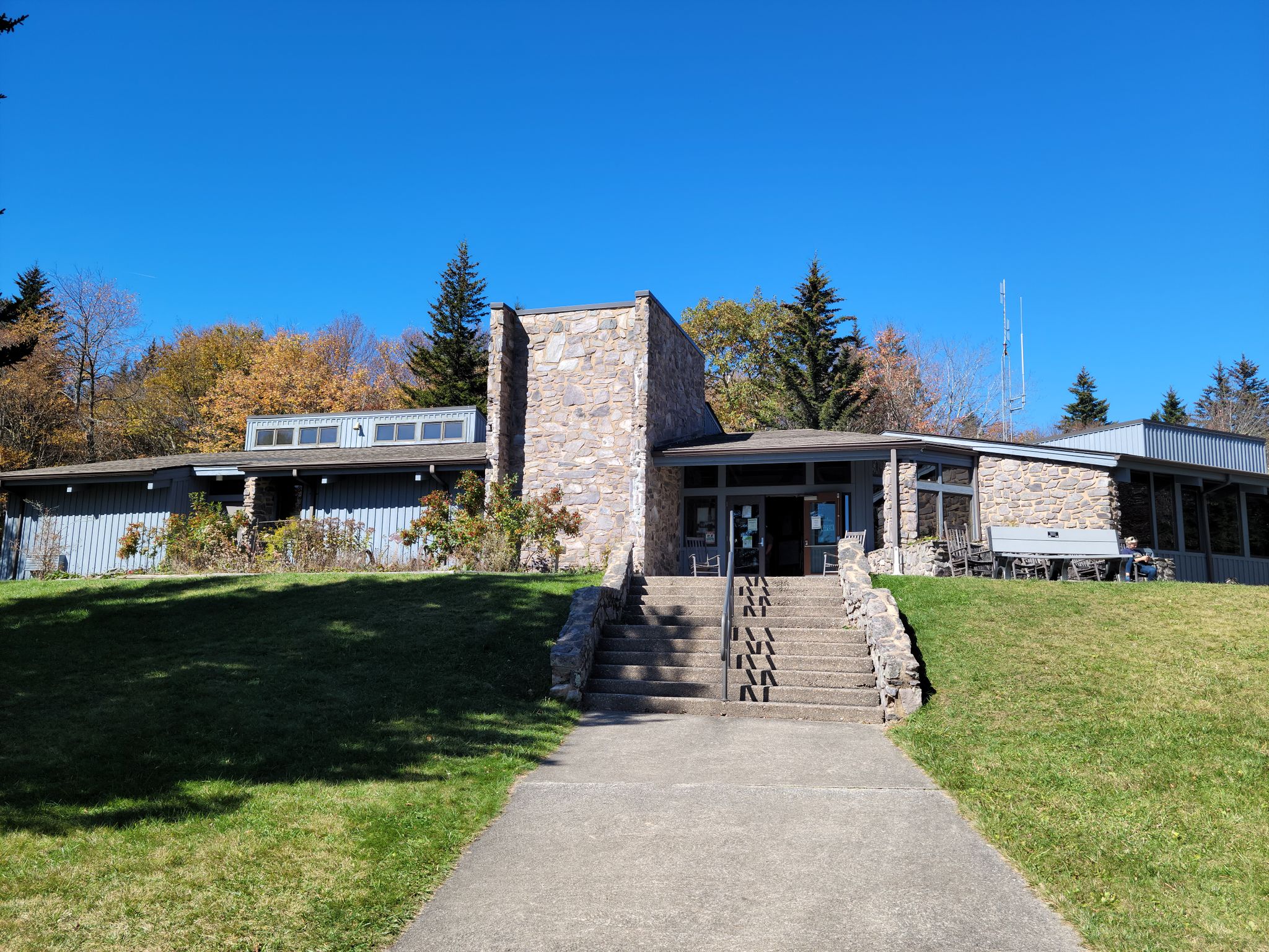 Modern building with stone facade on a grassy hill under a clear sky. - Haw Orchard Mountain – Big Pinnacle loop from Grayson Highlands State Park