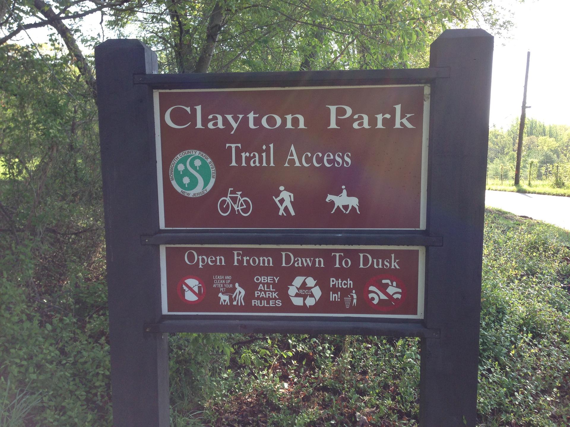 A brown park sign with white text and activity icons in bright sunlight.