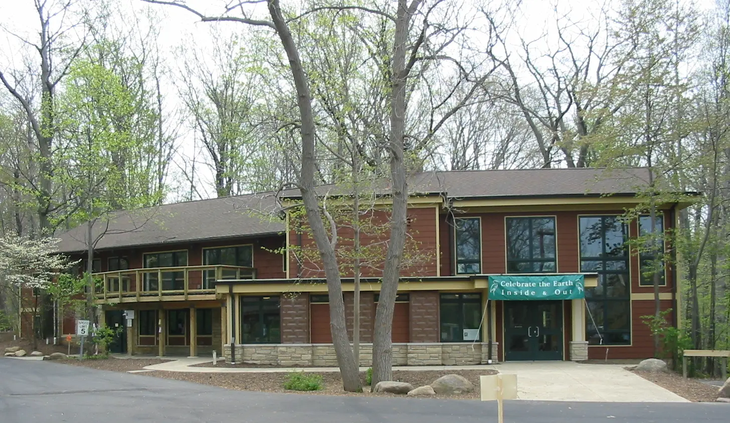 Large two-story building with brown siding and many windows, surrounded by trees.