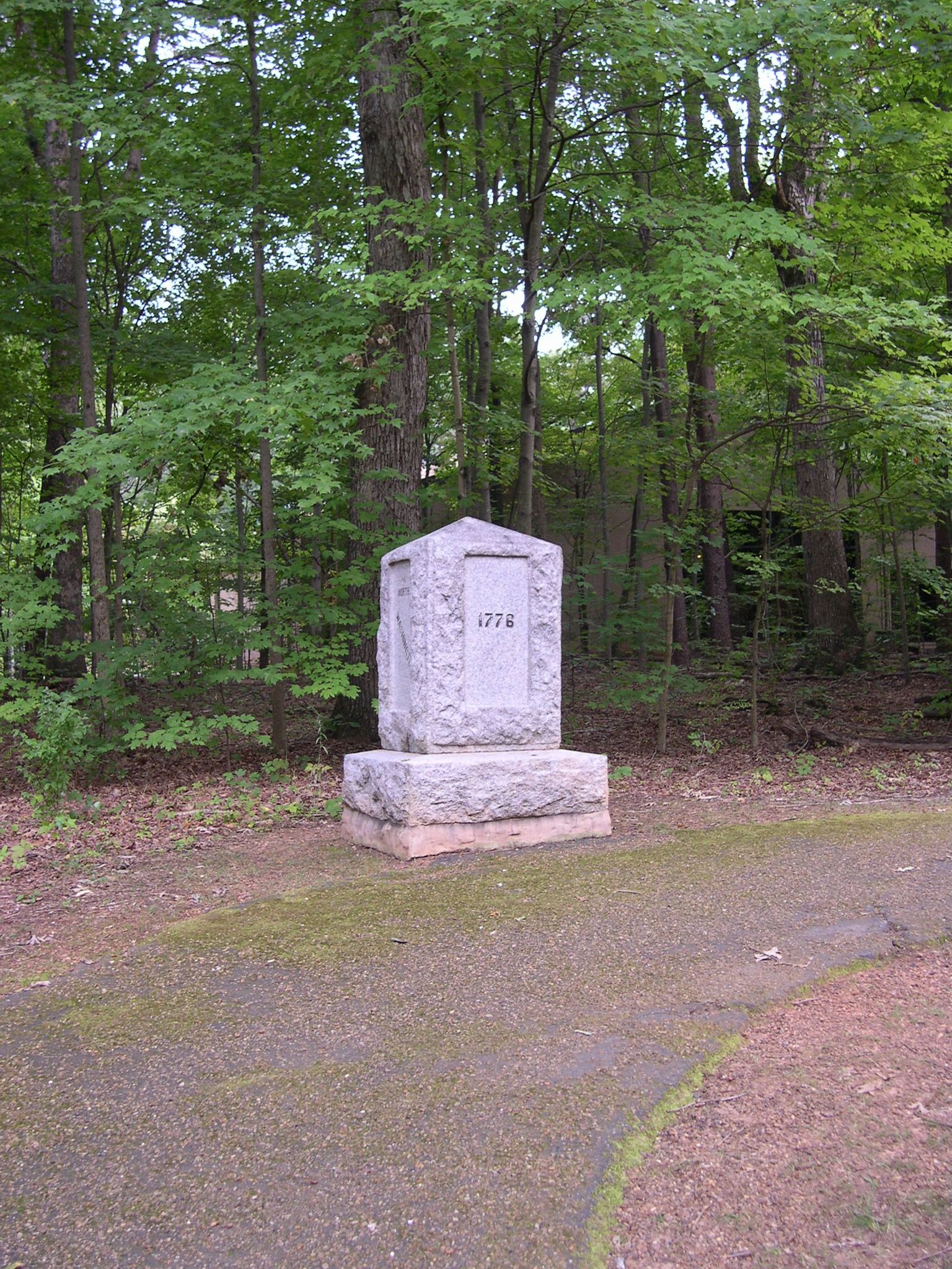 Stone monument with "1772" carved, surrounded by dense green forest, dappled light. - Greensboro Country Park loop via Auto Tour Road