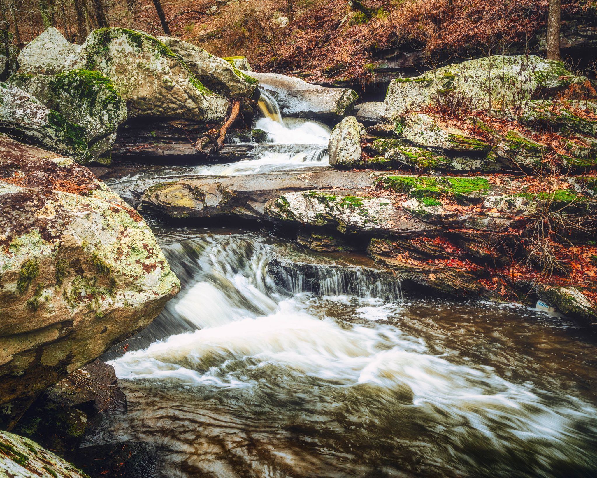Forest stream with white water rapids flowing over large moss-covered rocks. - Boy Scout Trail