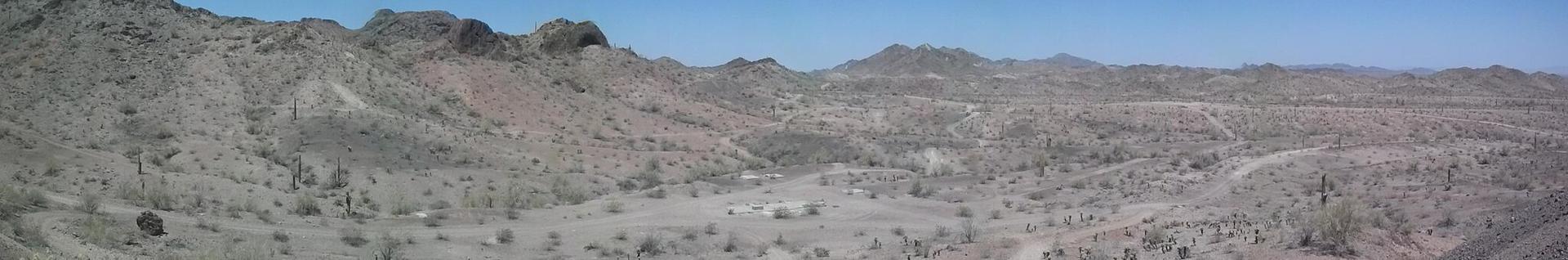 Panoramic view of a vast, arid desert landscape with distant mountains under a clear sky.