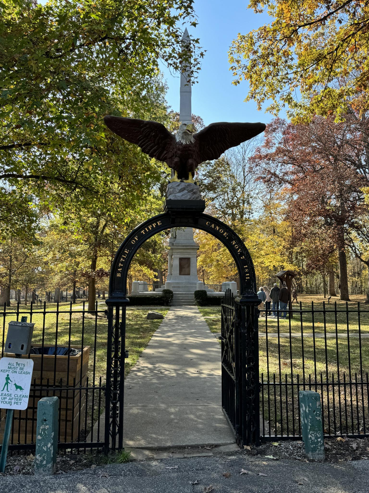 Sunny view of an eagle statue atop an archway leading to a park monument.