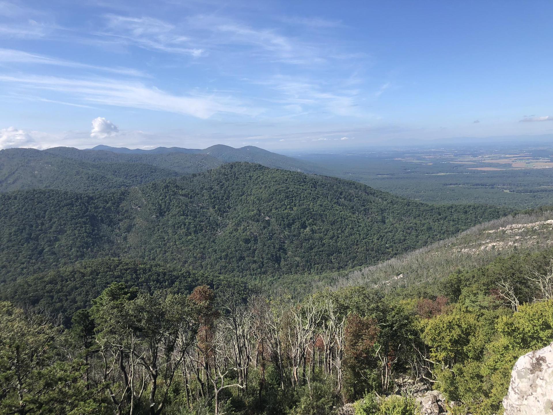 Vast green mountain range under a bright, partly cloudy sky.