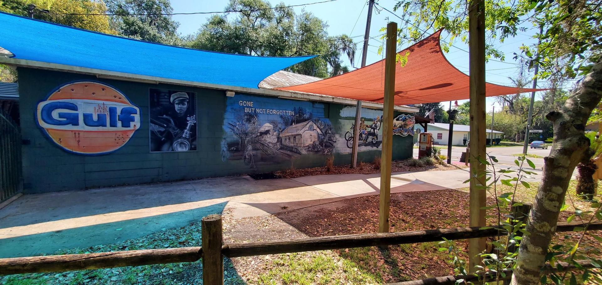 Building with murals and colorful shade sails under bright sunlight.