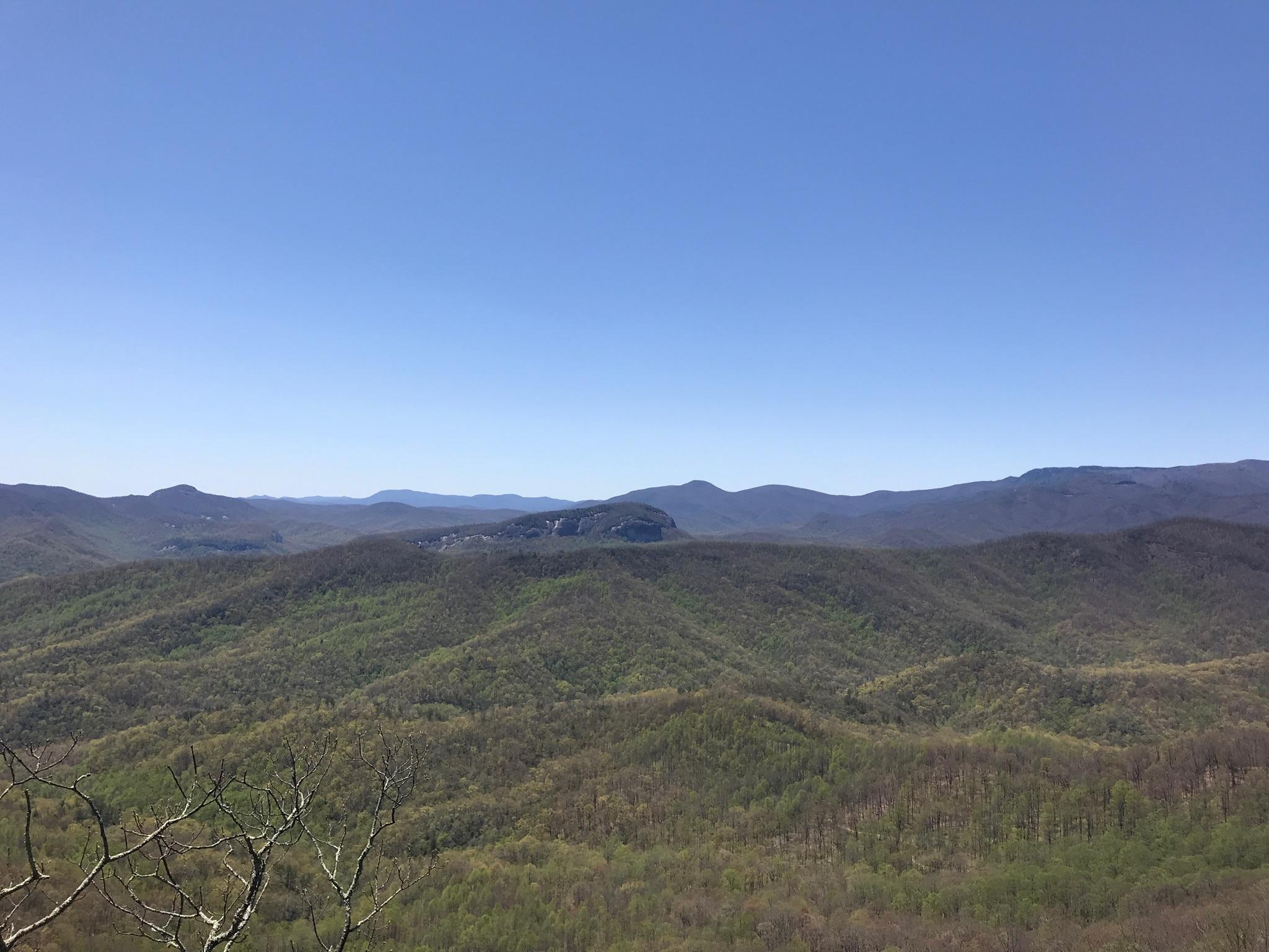 Vast panorama of green, rolling mountains under a clear blue sky.