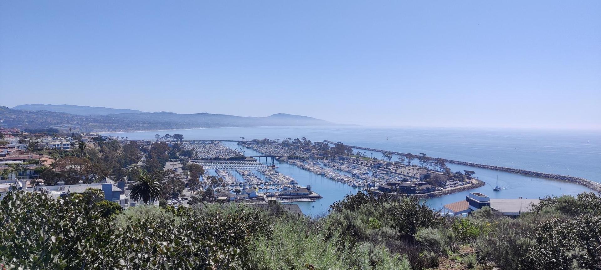 Panoramic view of a bustling marina and ocean under a bright, clear sky.