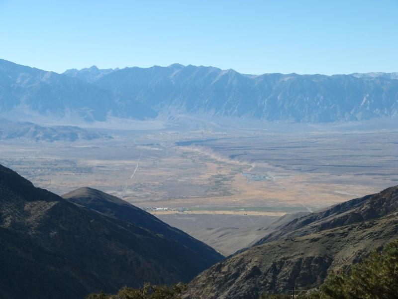 Vast arid valley framed by dark mountains under a clear blue sky.