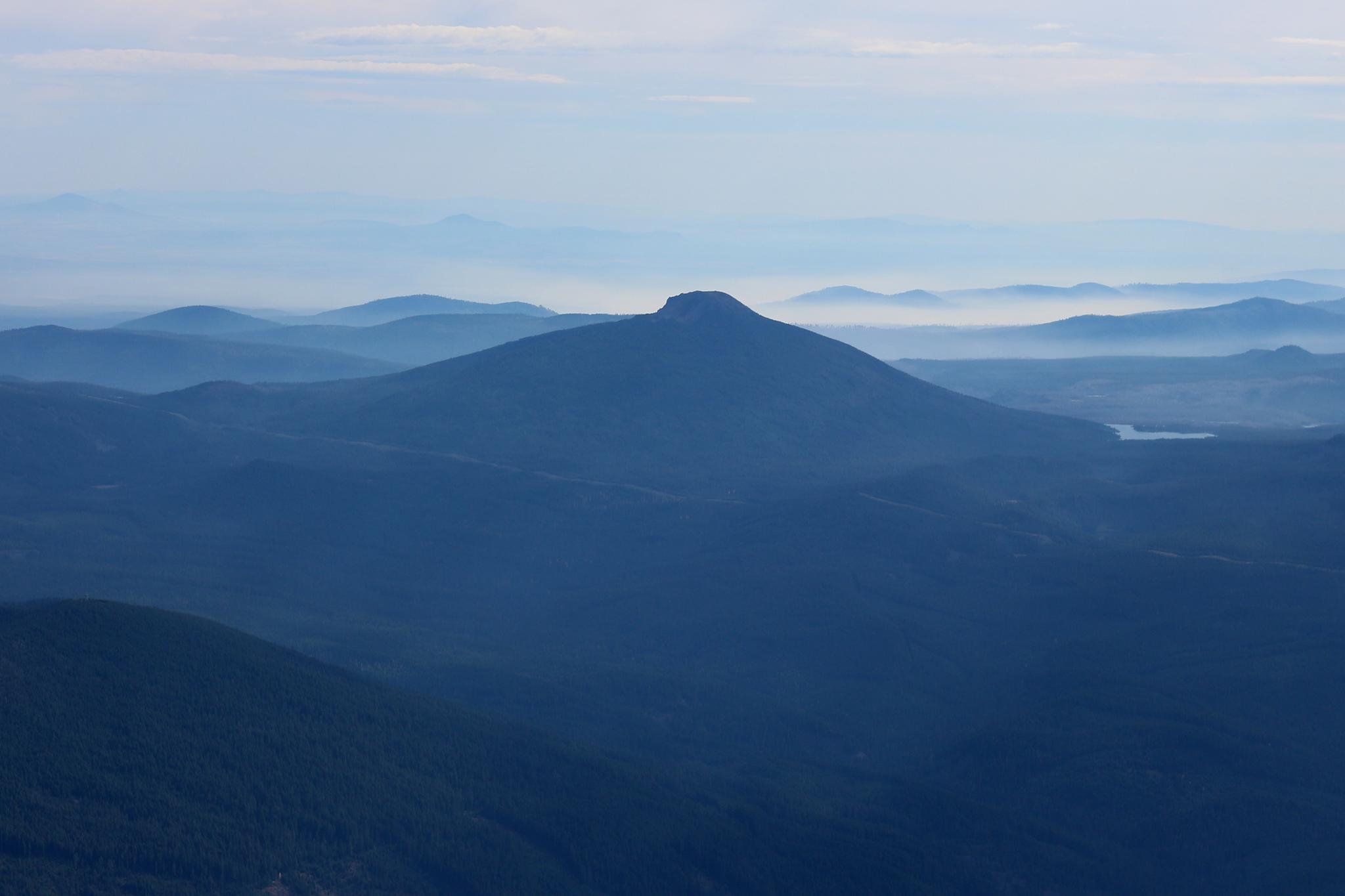 Distant, hazy blue mountains with a prominent peak and a small body of water.