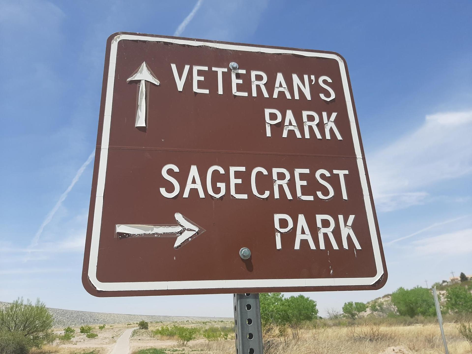 Brown directional sign with white text against a bright blue sky.