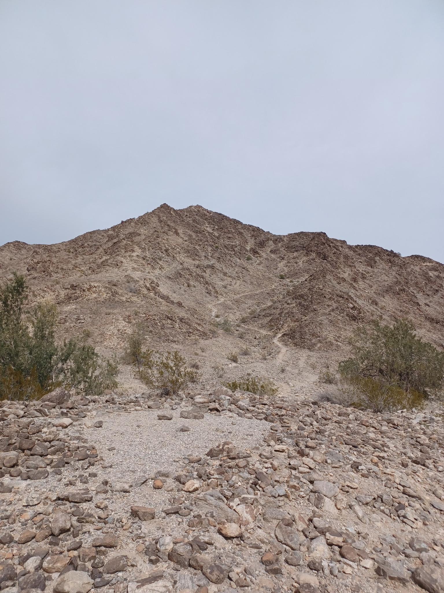 A barren, rocky mountain peak under an overcast, gray sky.