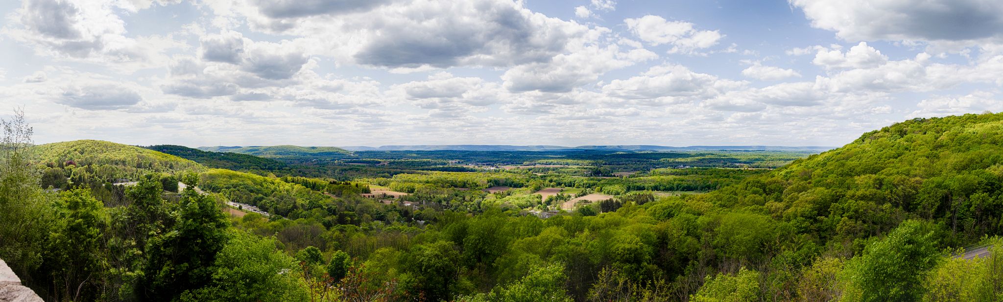 Panoramic view of lush green rolling hills under a partly cloudy sky. - Orange Switchback, White, and Blue Loop