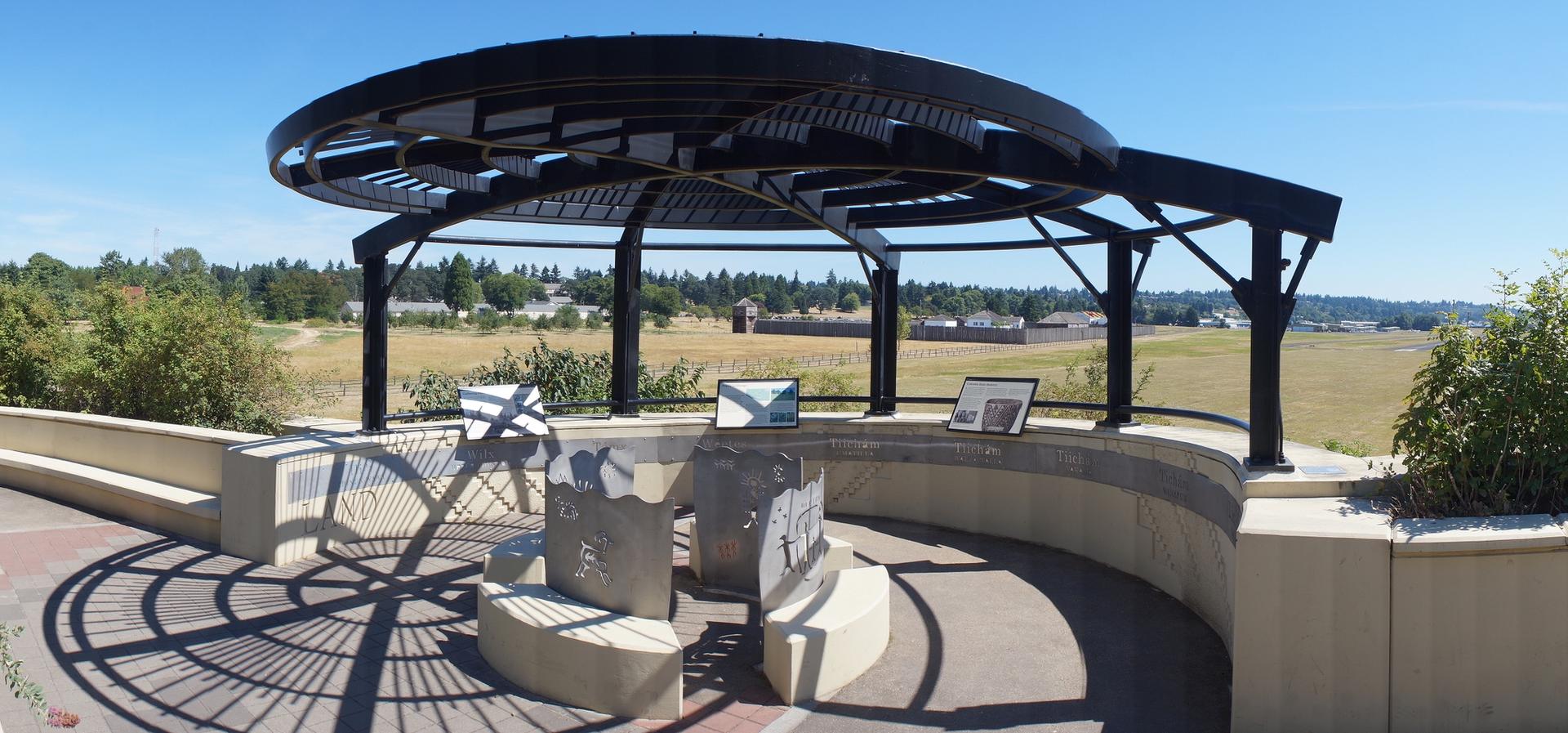 Sunny view of a modern outdoor structure with benches and displays in a field.