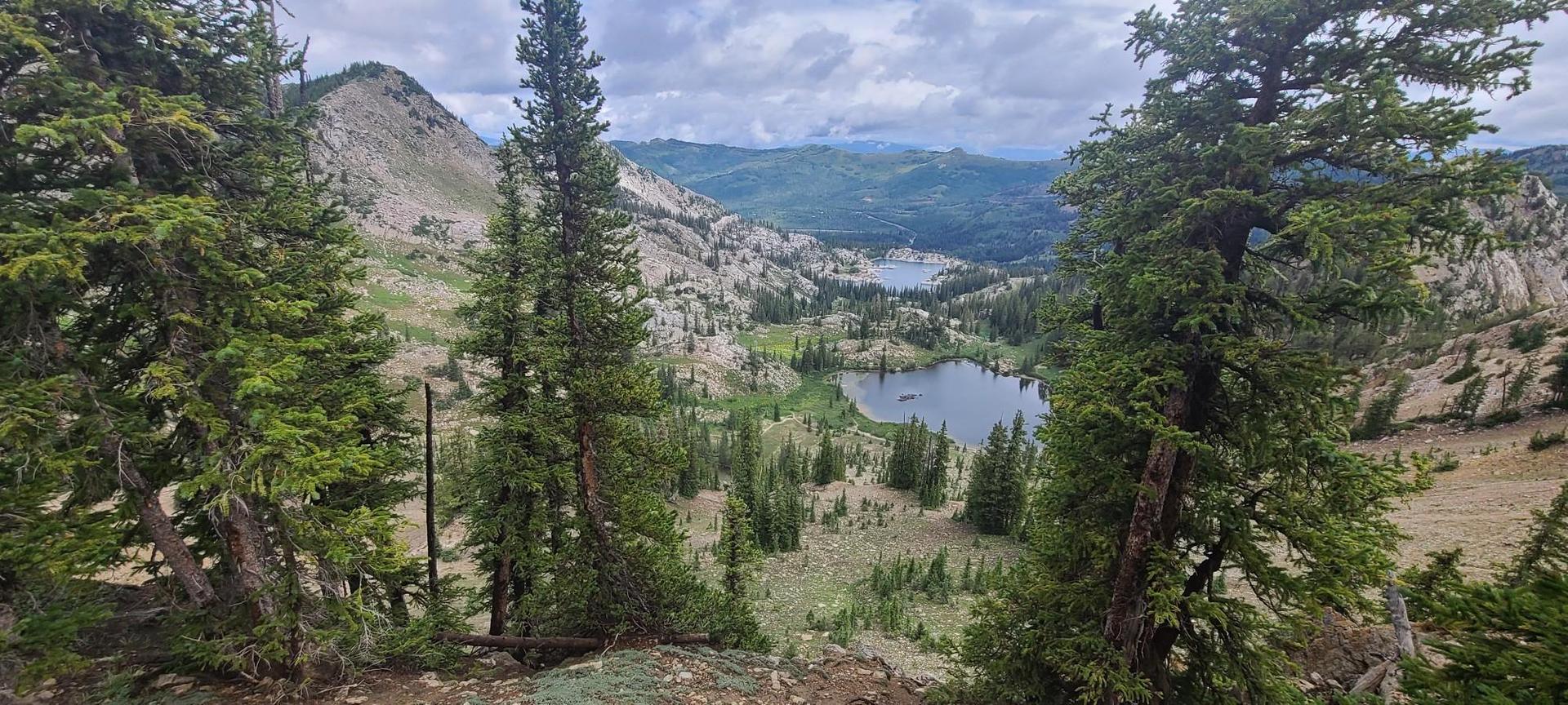 Overcast view of a mountain valley with two lakes surrounded by trees.