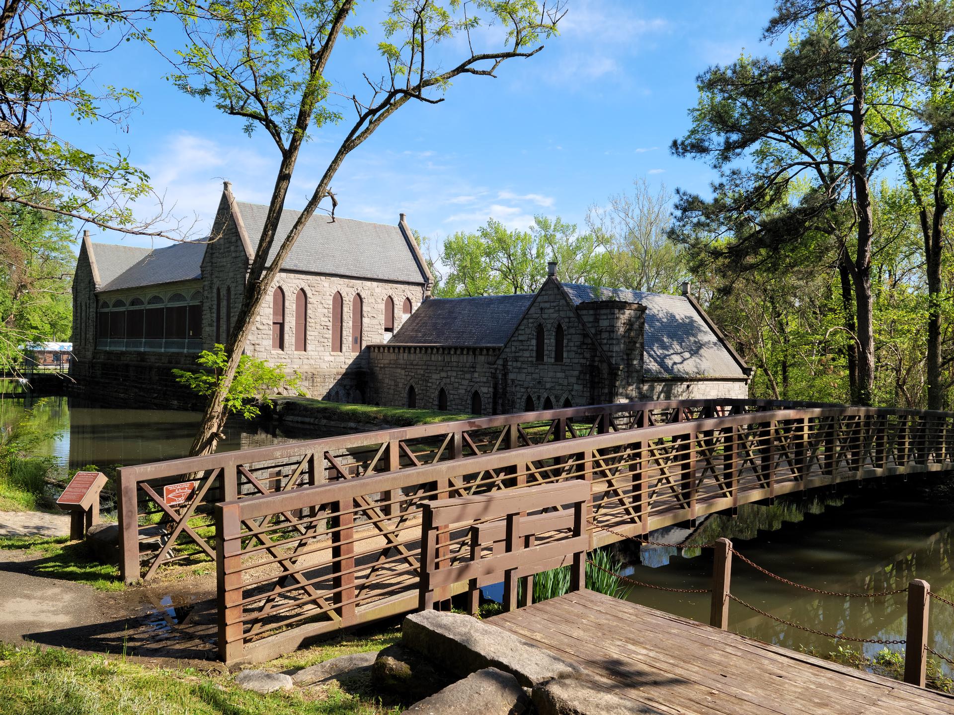 Stone buildings and a wooden bridge over water on a bright, sunny day.