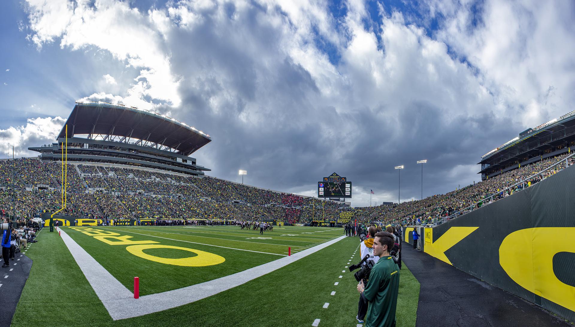 Panoramic view of a crowded football stadium under a cloudy sky.