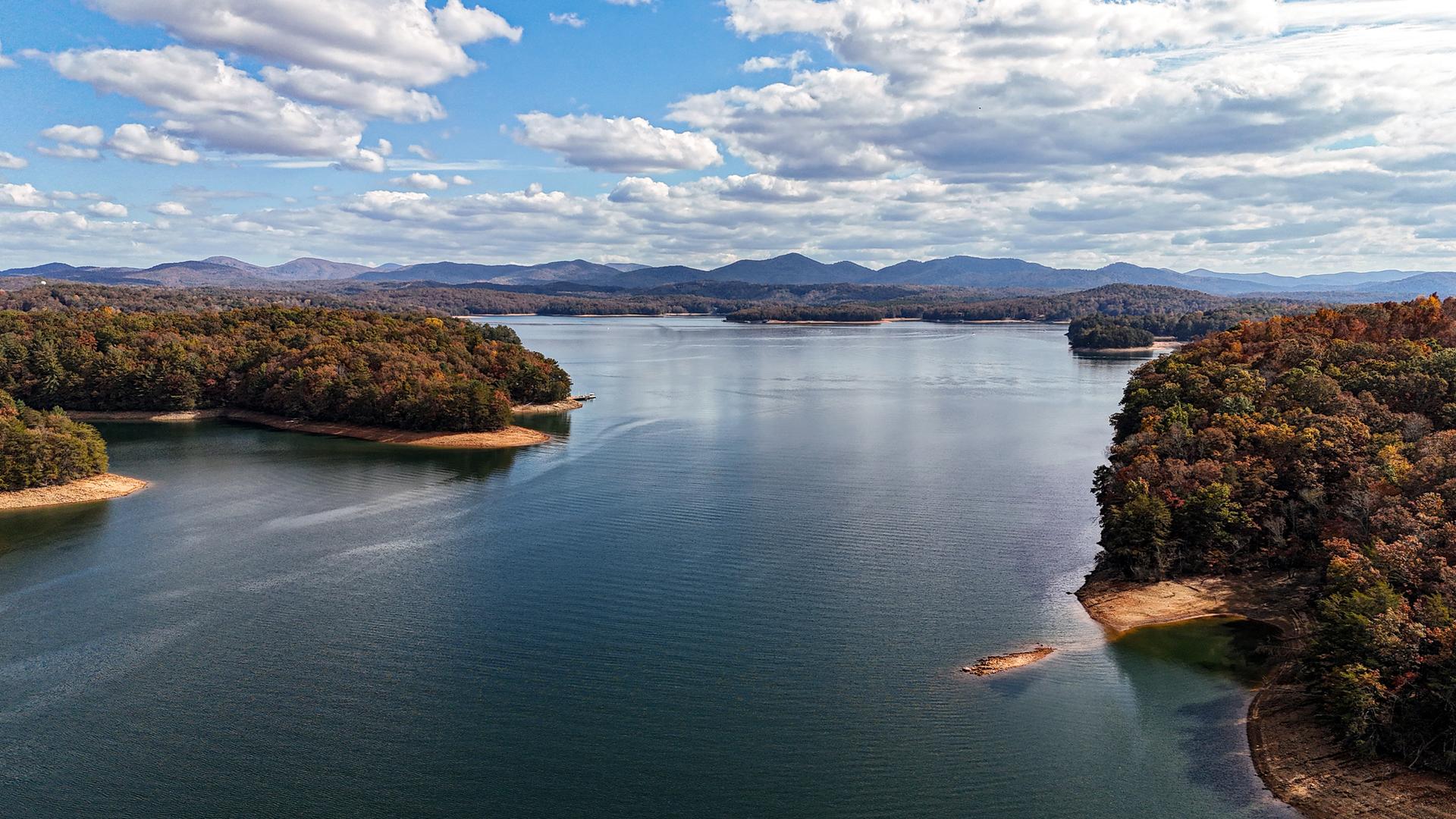 Aerial view of a large lake surrounded by autumn forested hills.