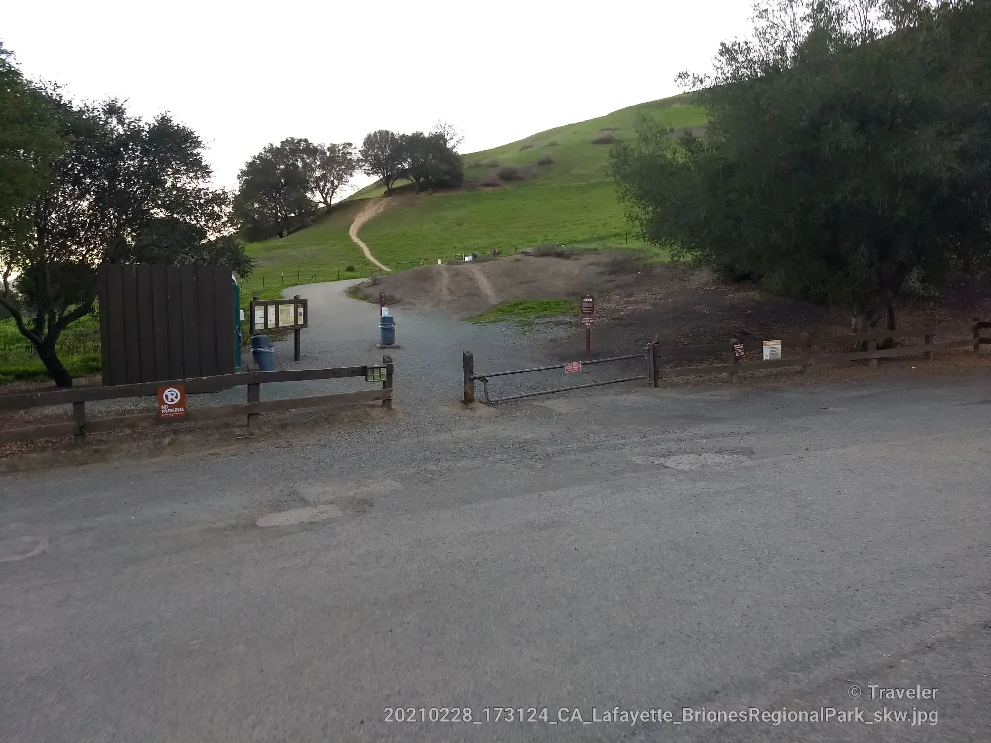 Trailhead entrance with a metal gate, signs, and a path leading up a green hill. - Lafayette Ridge and Springhill Trail Loop