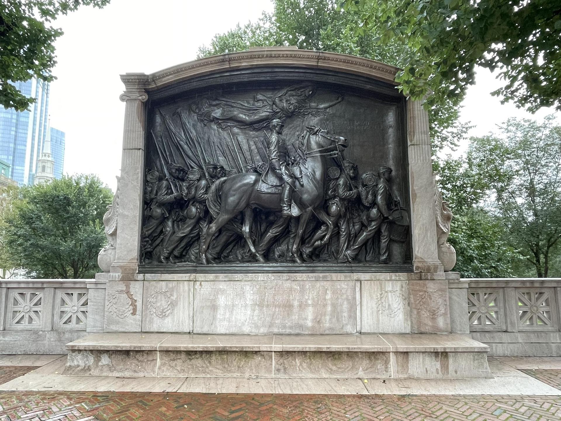 An ornate bronze relief sculpture depicting figures on horseback and on foot.