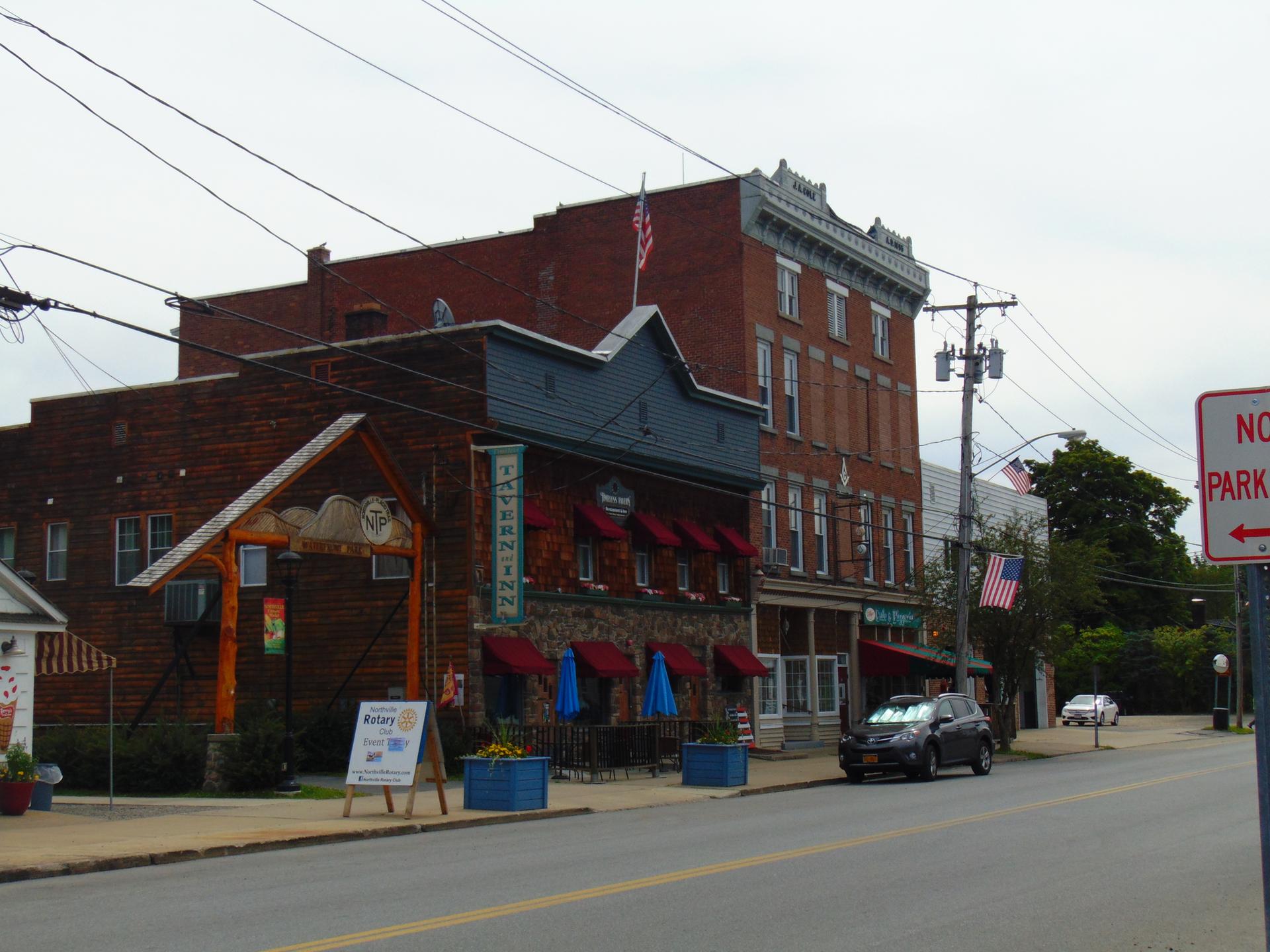 Quaint street with historic brick buildings and power lines on an overcast day.