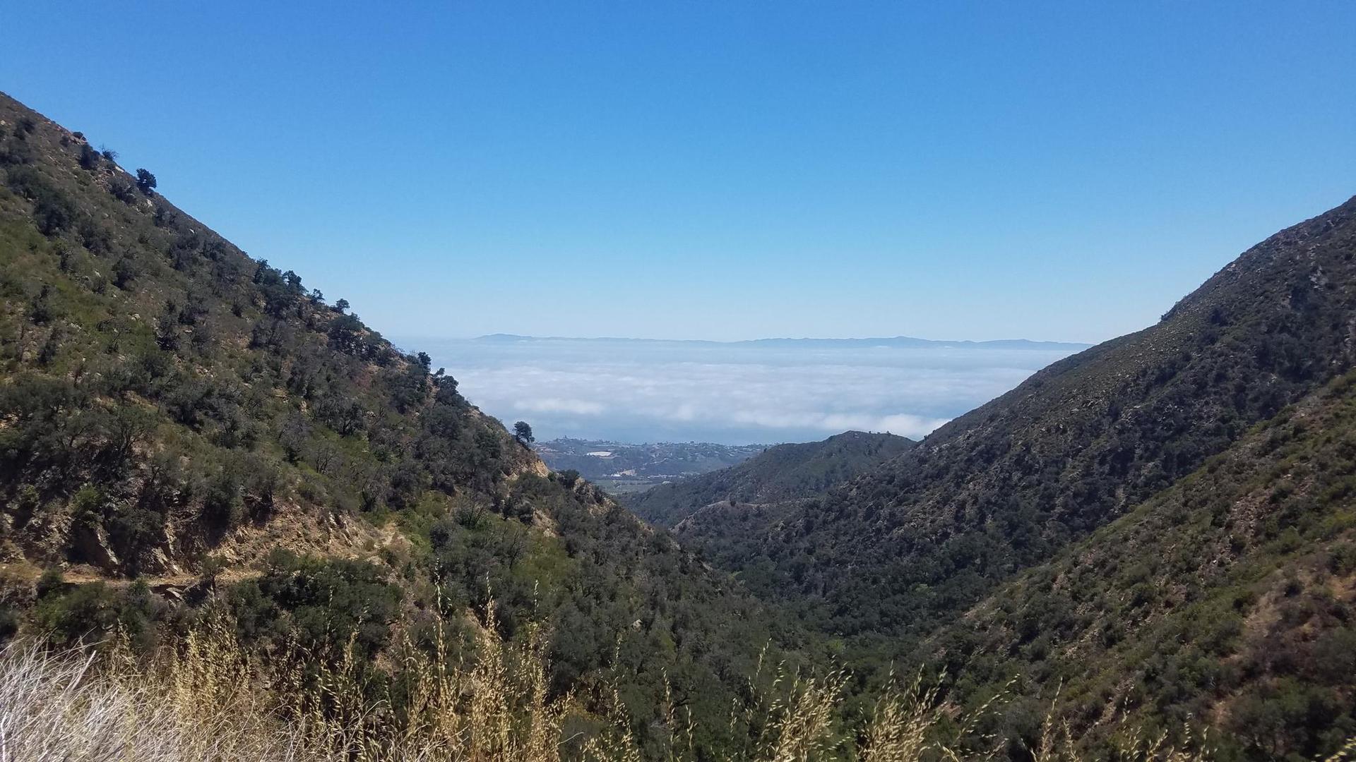 A valley view with distant fog layer under a clear blue sky.