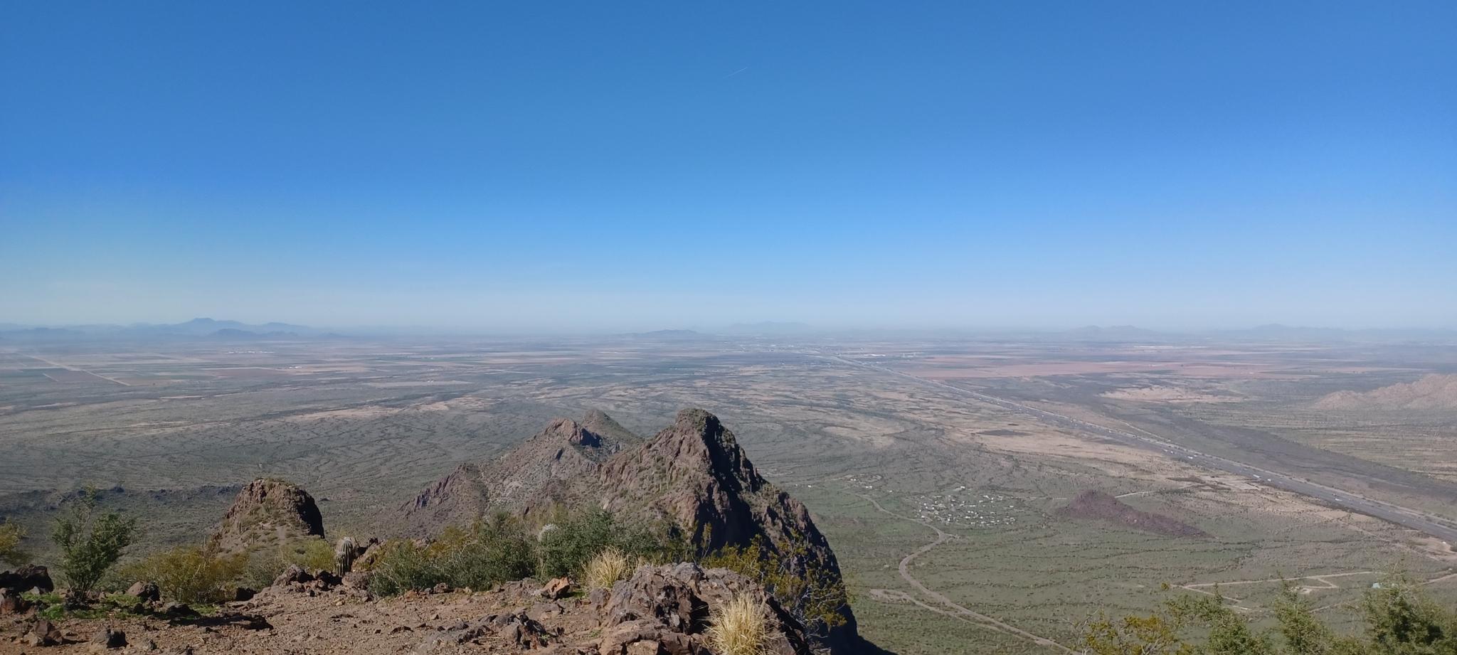 Panoramic view of rugged desert mountains and vast plains under a clear sky.