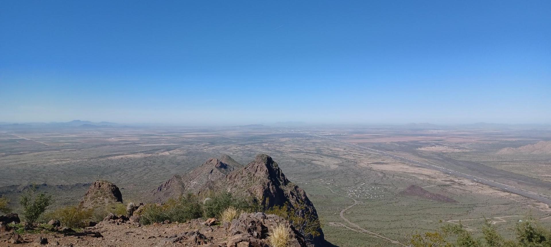 Panoramic view of rugged desert mountains and vast plains under a clear sky.