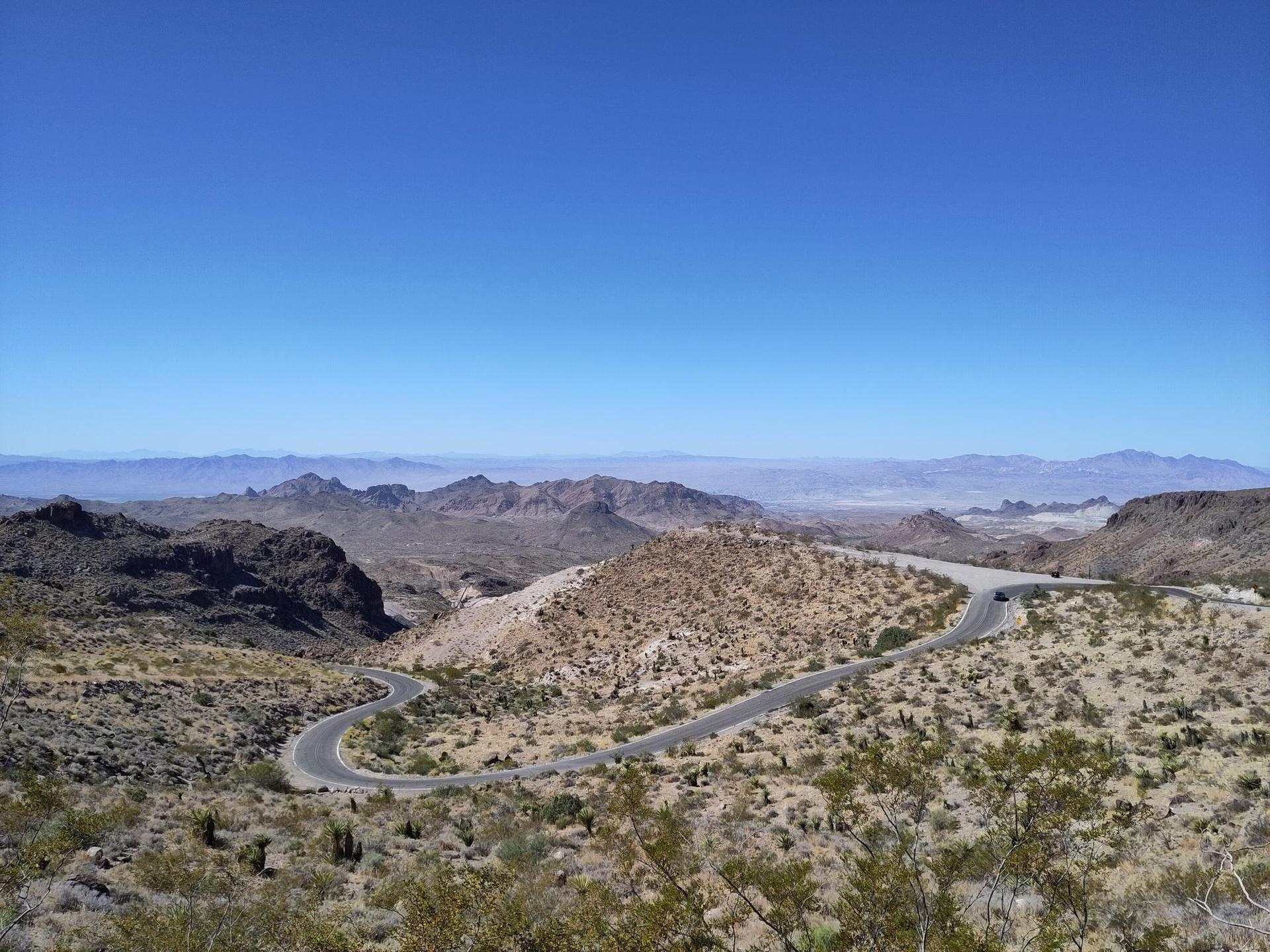 Winding road through vast desert mountains under a clear blue sky.