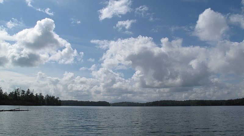 A wide lake with forested shores under a bright, partly cloudy sky. - Lake James view – Lake James loop from Trailhead Kiosk