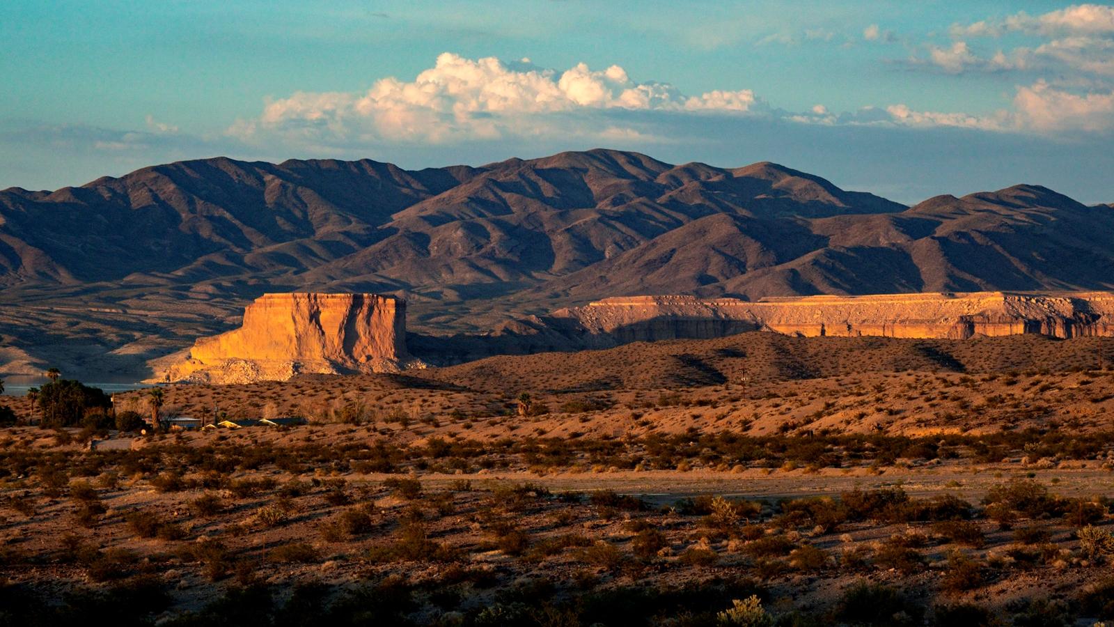 Golden hour light illuminates desert mountains and flat-topped mesas.