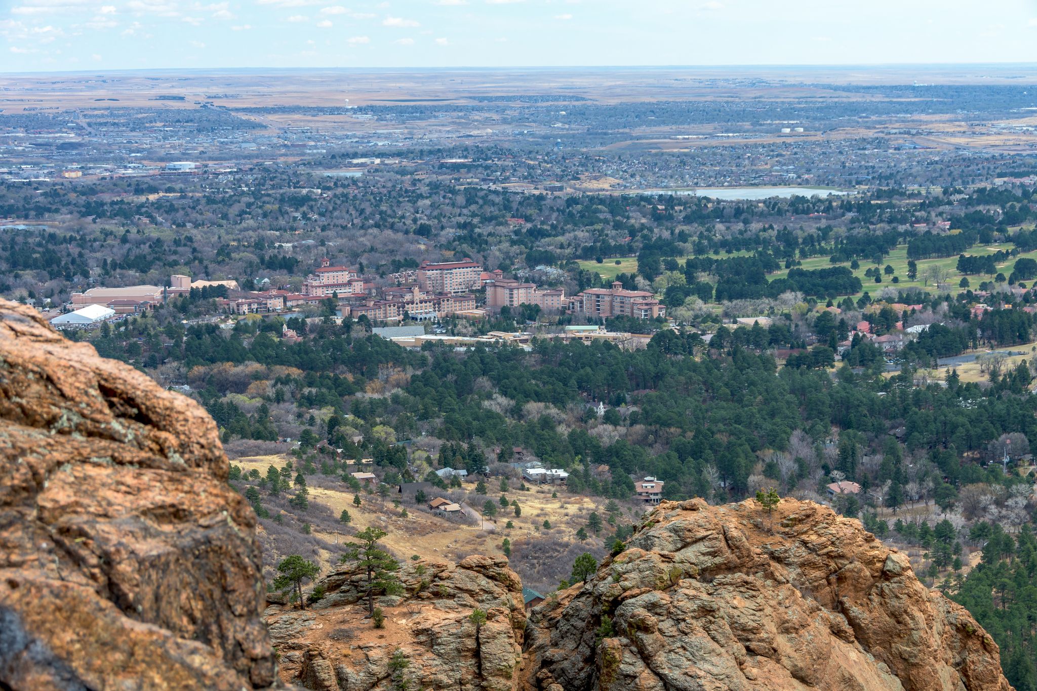 Panoramic view from rocky cliffs overlooking a city and forested valley under diffused light. - Gold Camp Road Loop