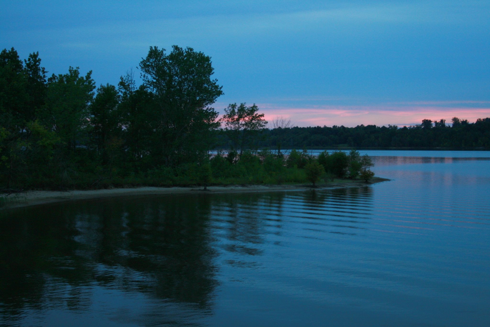 A calm lake at dusk with a tree-lined shore and pink-blue sky. - Falls Lake Causeway – Falls Lake Causeway loop from Crabtree Creek Watershed Project