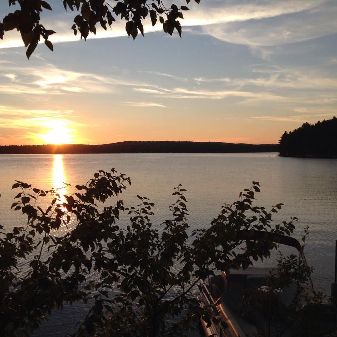 Golden sunset over a calm lake with silhouetted trees and reflections. - Great East Lake loop from Acton